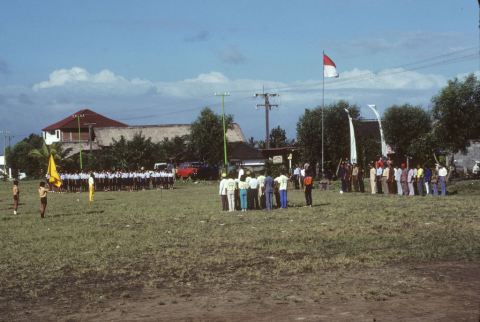 Teachers, staff, and students gather in schoolyard to salute flag and sing patriotic songs