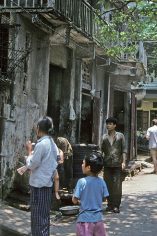 Several people, including woman with small child, look from street into residence