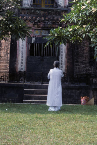 Woman in long white robes faces Buddhist temple built in Hue in 1844