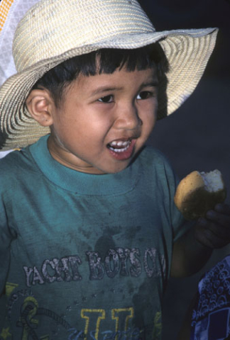Small boy eating cake in green T-shirt and Panama-style hat north of Qui Nho'n