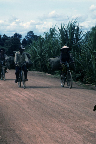 Three people bicycle along a dirt road near Siem Reap